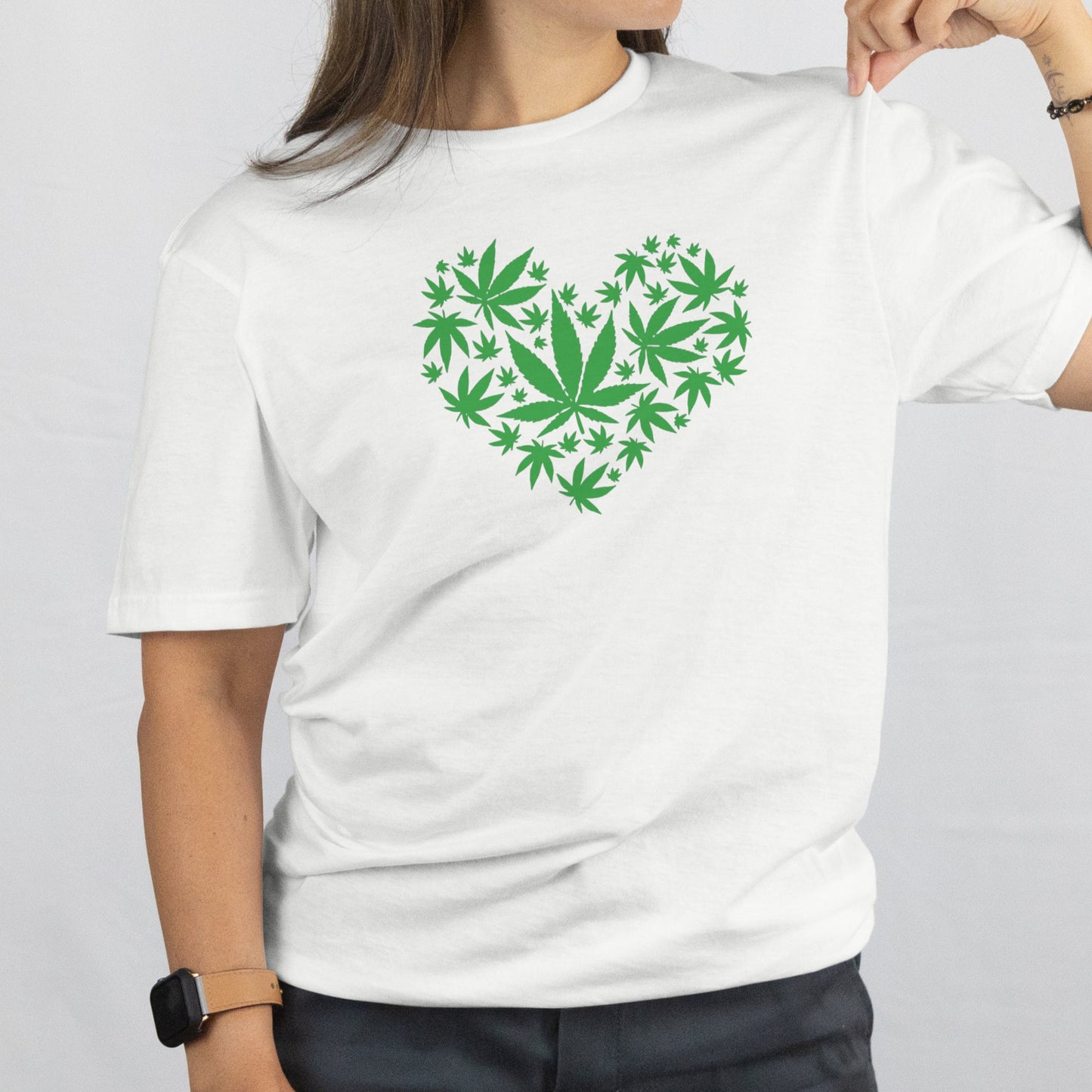 Person wearing a white t-shirt with a green heart design on a plain background