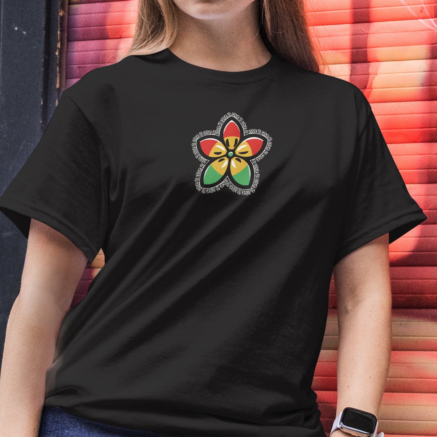 Person wearing a black t-shirt with a colorful flower design in front of a vibrant mural.