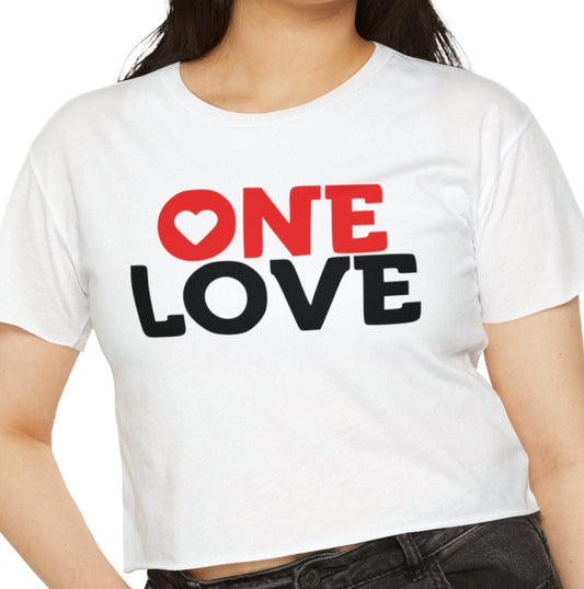 A woman wearing a white crop top with the text 'ONE LOVE' printed in red on the front, paired with black jeans.
