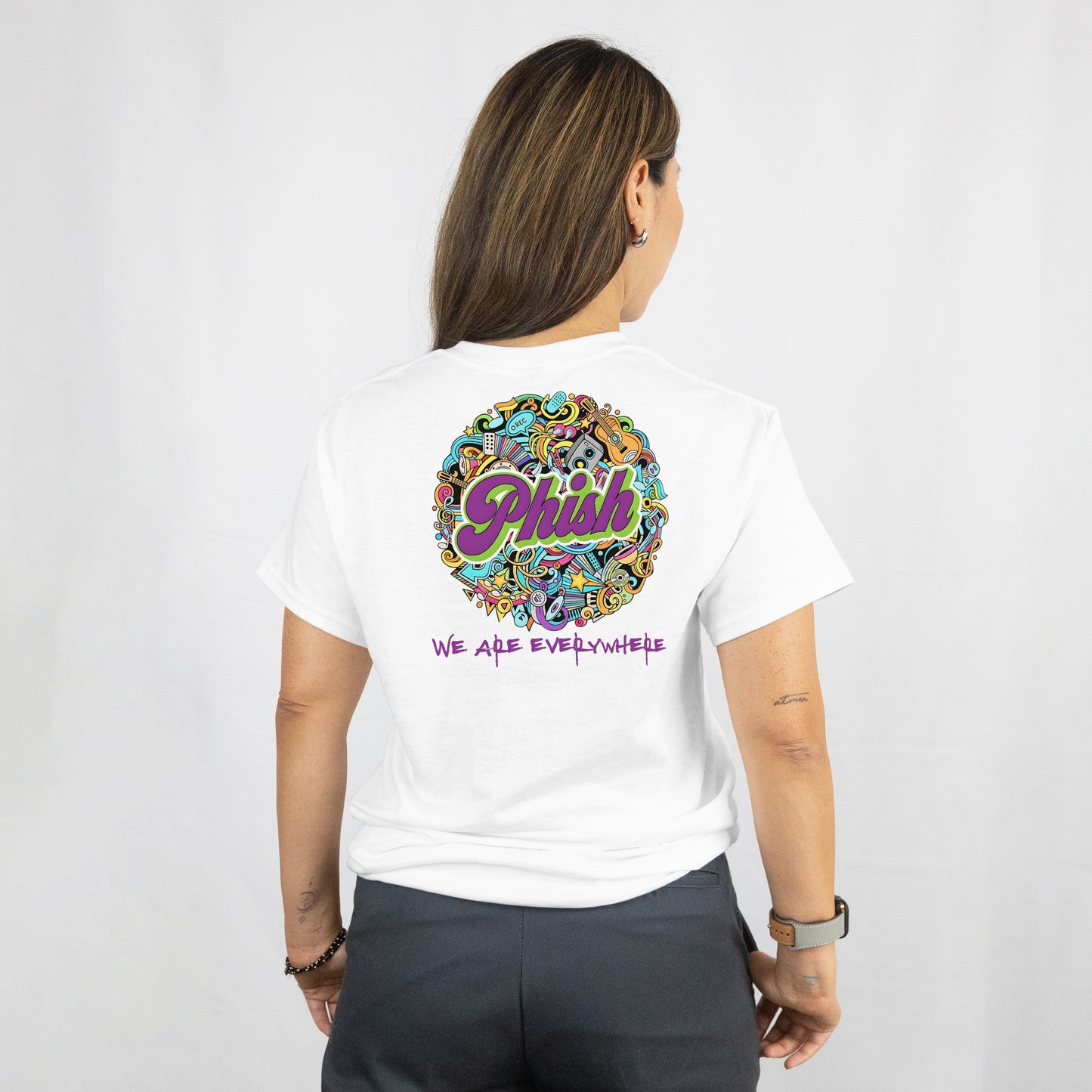 Person wearing a white t-shirt with colorful 'Phish' graphic design on the back.