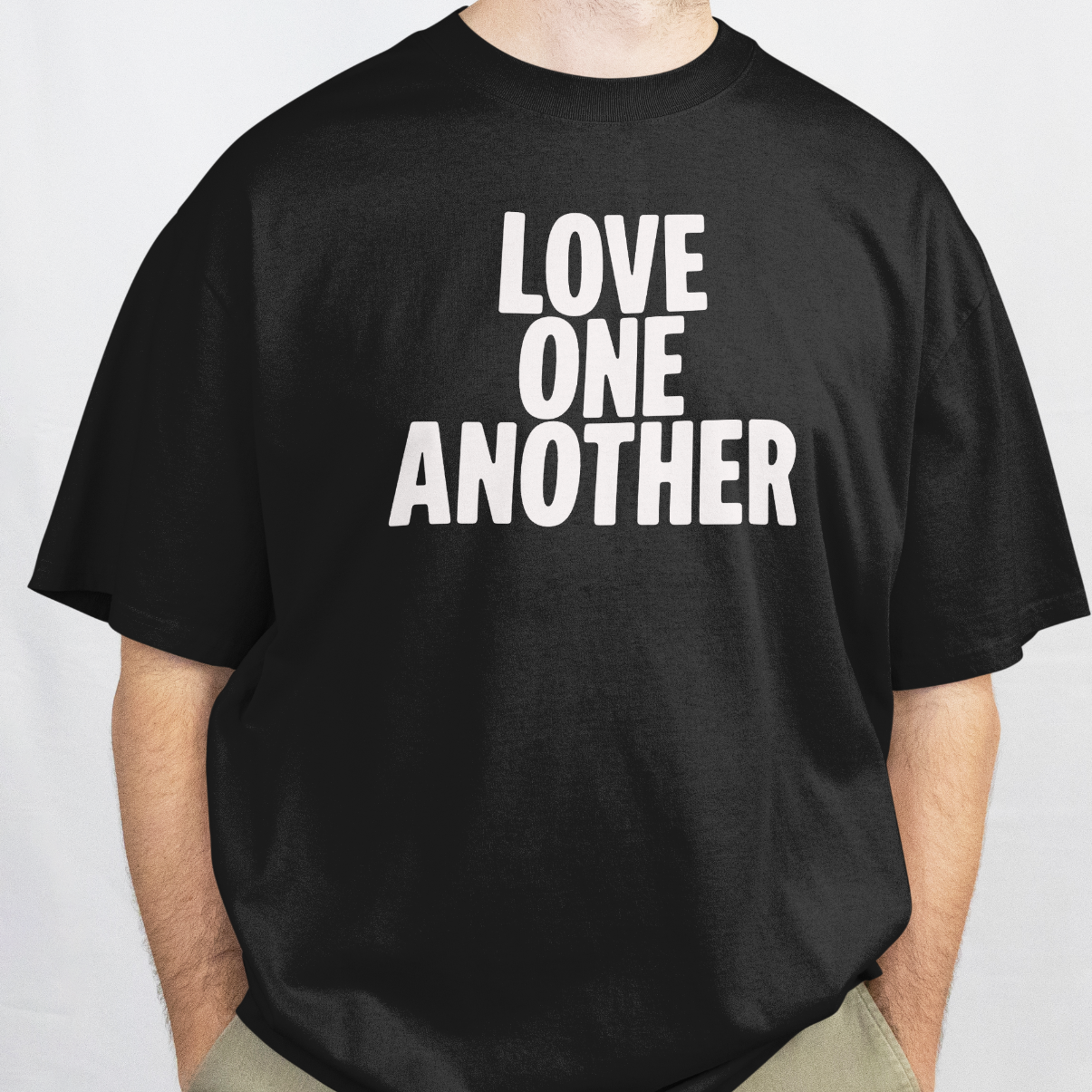 Man wearing a black t-shirt with 'LOVE ONE ANOTHER' text on a white background
