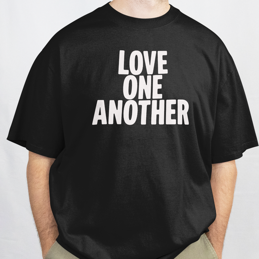 Man wearing a black t-shirt with 'LOVE ONE ANOTHER' text on a white background