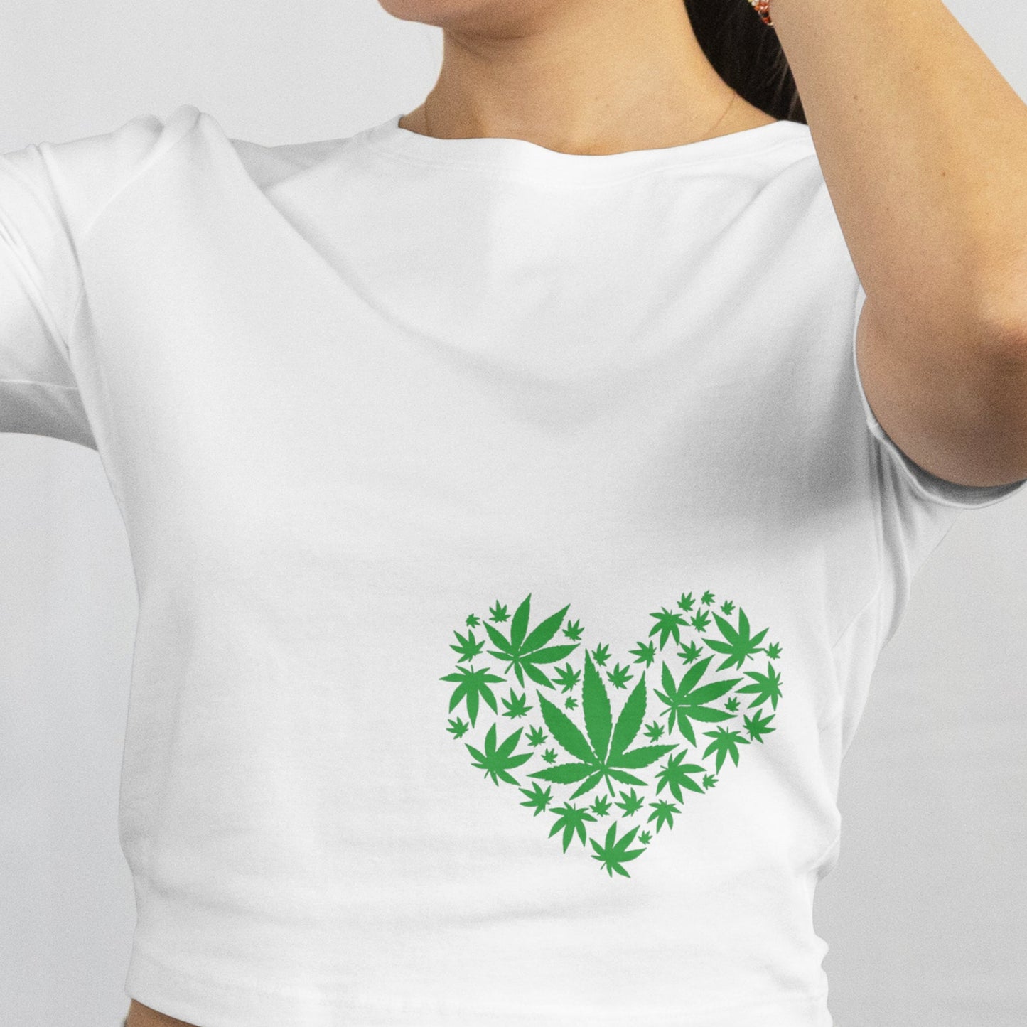 Woman wearing a white t-shirt with a green heart design and sunglasses, on a plain background