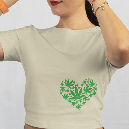 Woman wearing a beige t-shirt with a green heart design and sunglasses, against a plain background