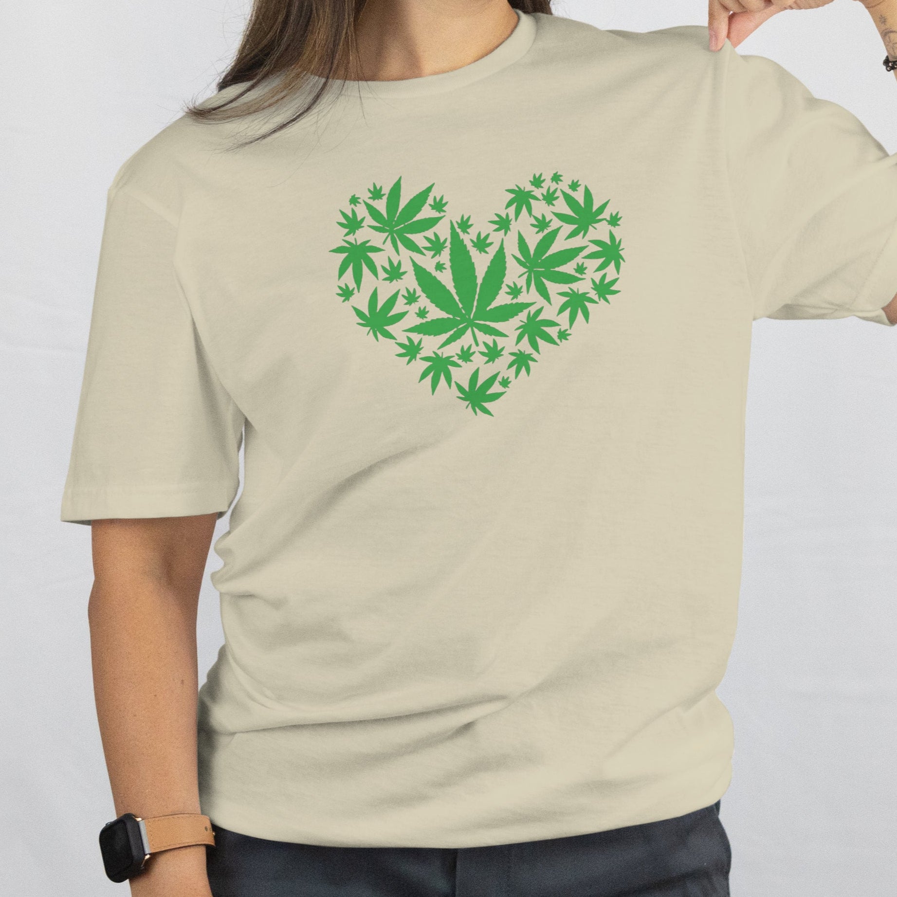 Person wearing a beige t-shirt with a green heart design made of leaf shapes on a white background
