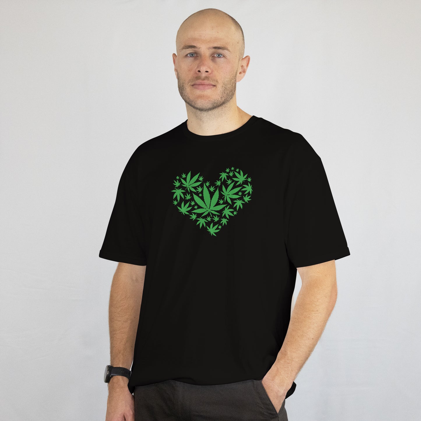 Man wearing a black t-shirt with a green heart design on a plain background
