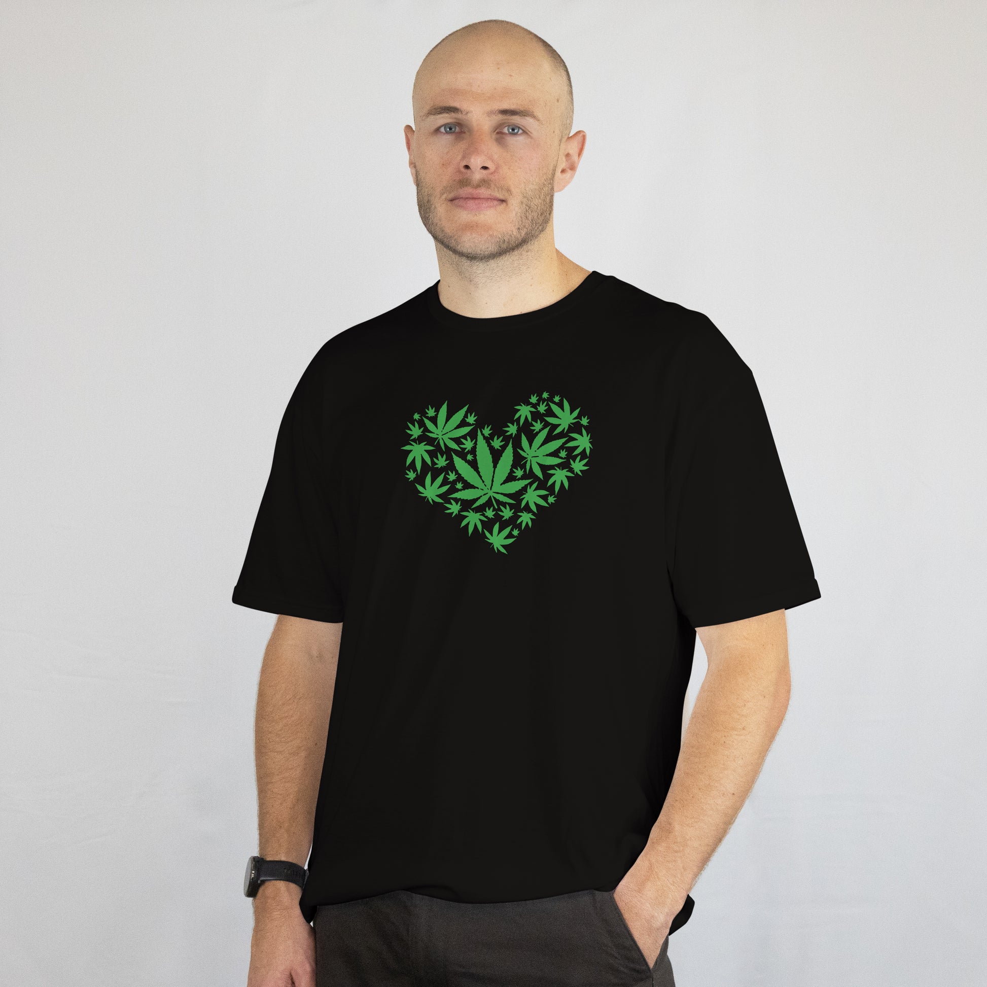 Man wearing a black t-shirt with a green heart design on a plain background