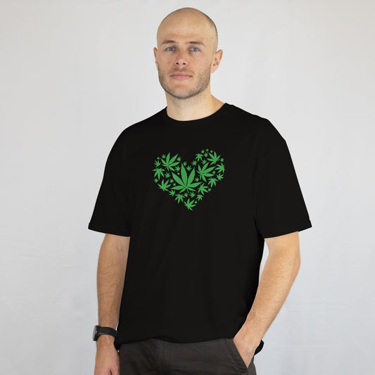Man wearing a black t-shirt with a green heart design on a plain background