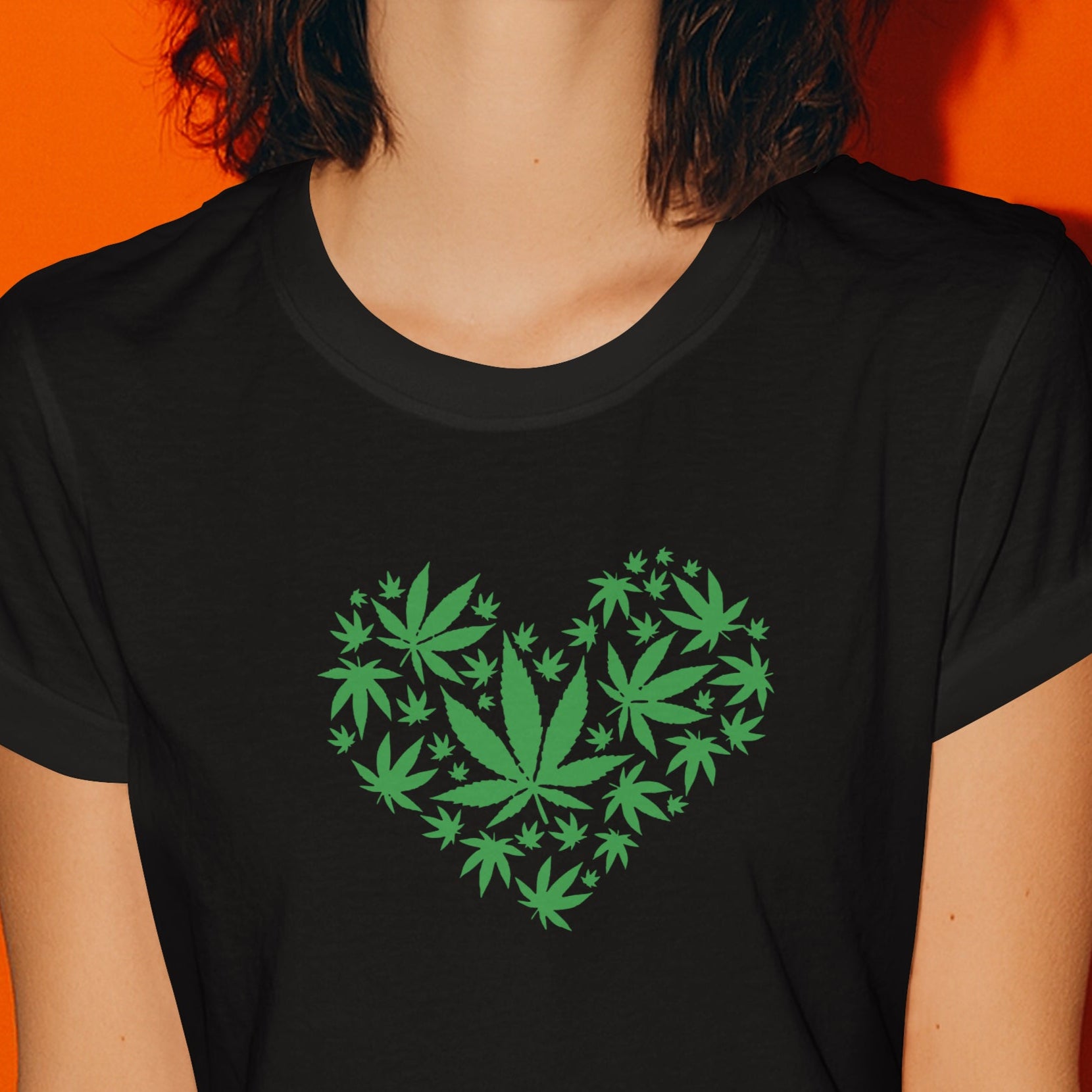 Woman wearing a black t-shirt with green leaf design on an orange background