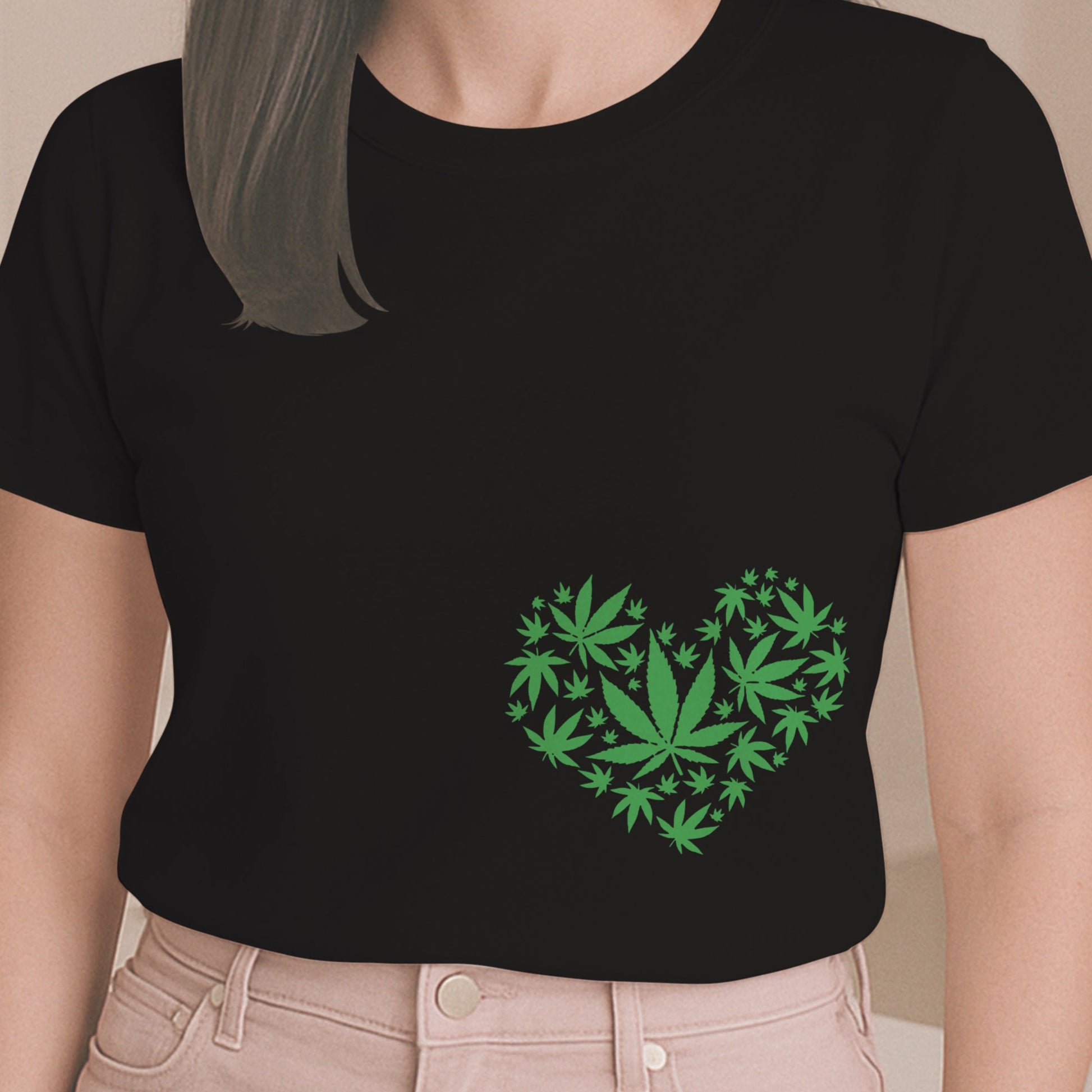 Person wearing a black t-shirt with green cannabis leaf design in the shape of a heart.
