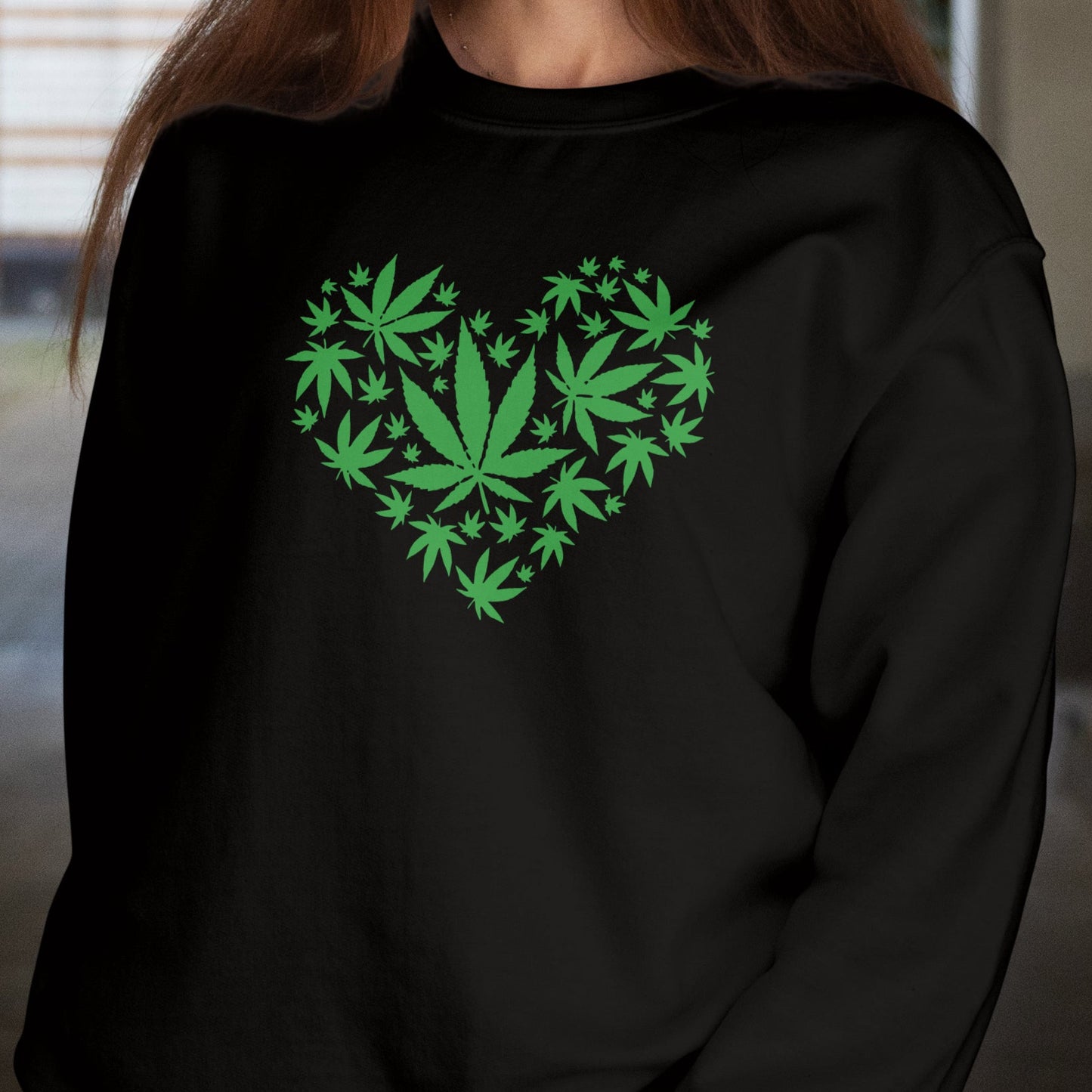 Person wearing a black sweatshirt with green leaf design in the shape of a heart.