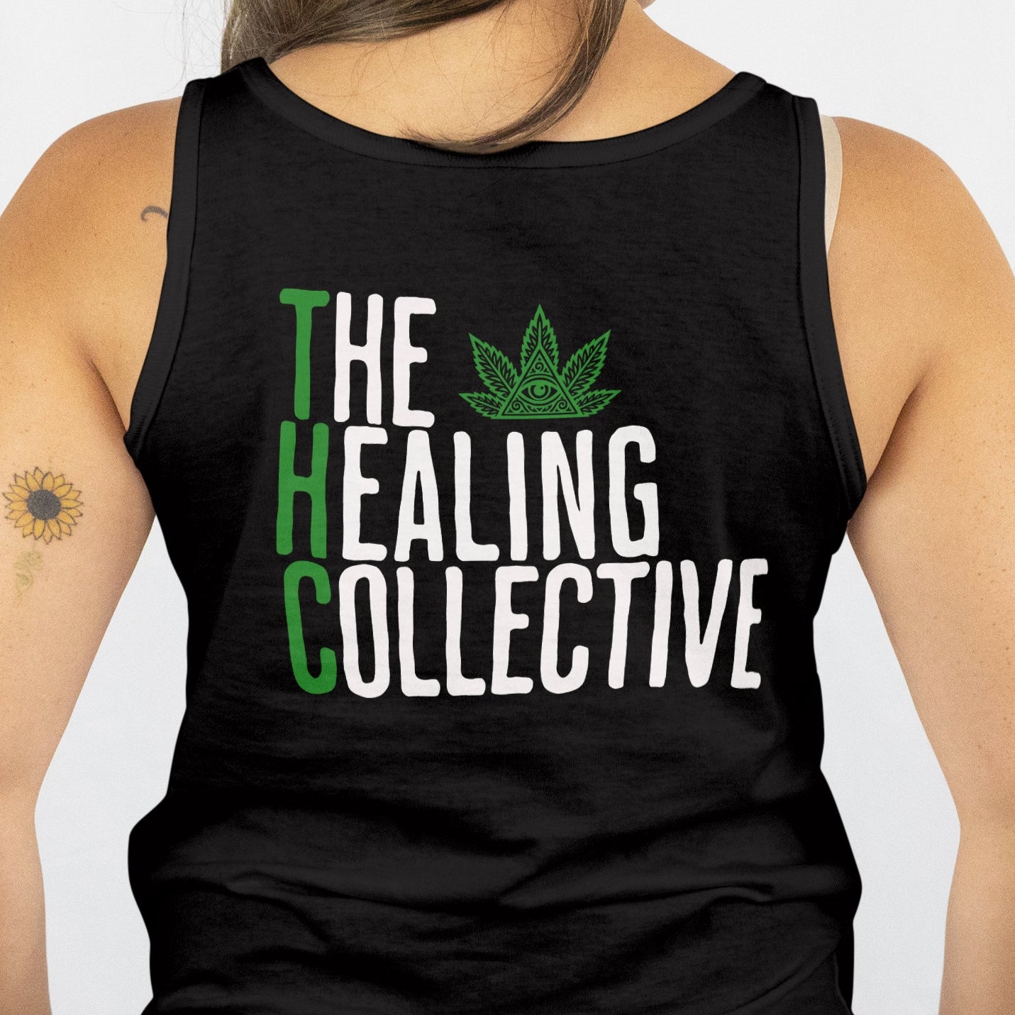 Person wearing a black tank top with 'The Healing Collective' text and logo on the back.