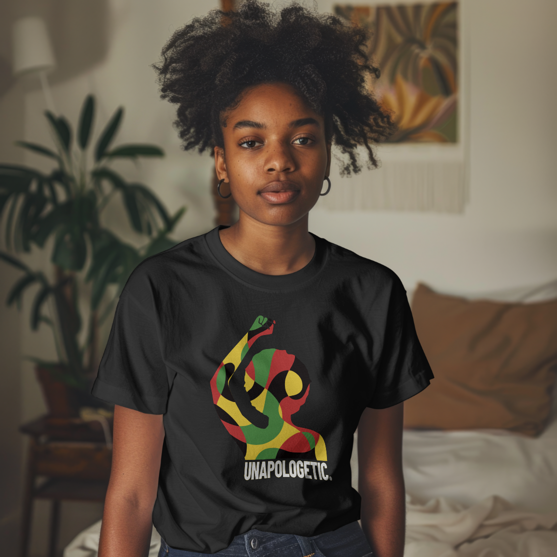 Person wearing a black t-shirt with a colorful design and text in a room with plants and furniture.